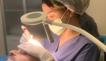 Medico esegue un trapianto di capelli sotto una lampada chirurgica.