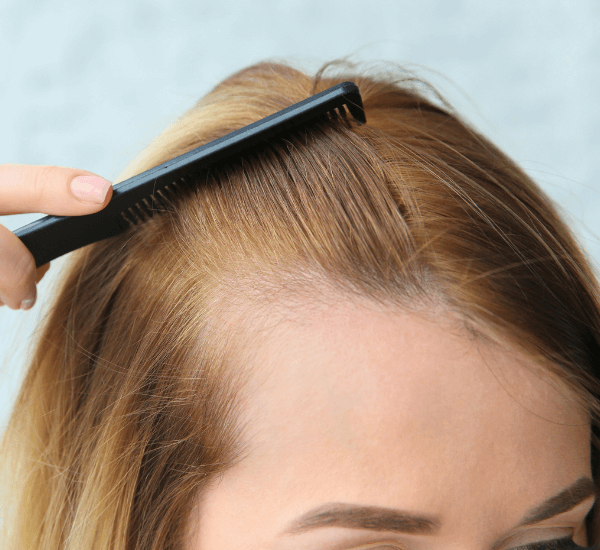 A woman combing her hair, which appears visibly thicker